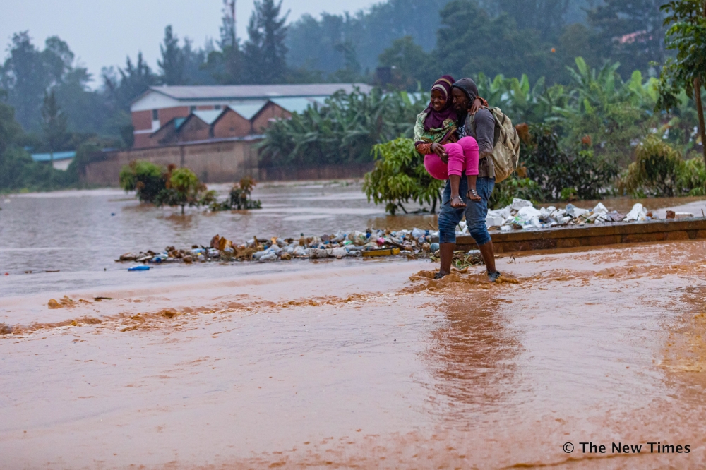 Residents wade through a flooded street in Kigali. METEO Rwanda has alerted that many parts of the country will continue to experience above normal rainfall amount, in the next 10 days. File