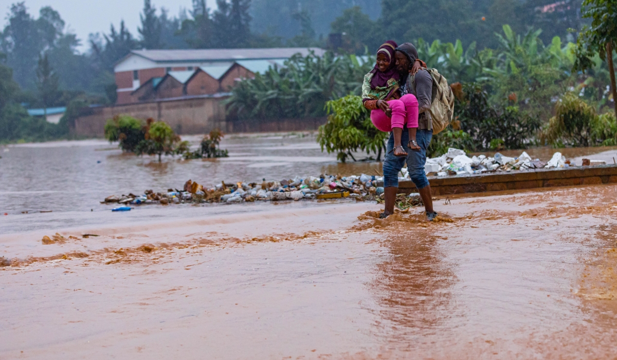 Residents wade through a flooded street in Kigali. METEO Rwanda has alerted that many parts of the country will continue to experience above normal rainfall amount, in the next 10 days. File