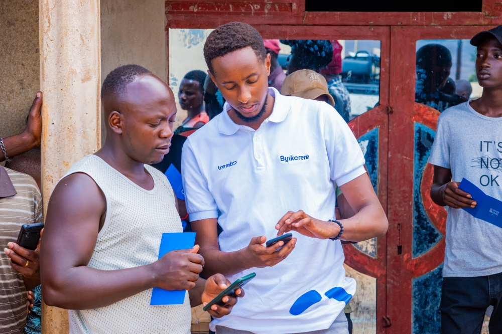 Irembo staff shows a resident how he can pay some services through Irembo online platform during their campaign. Courtesy