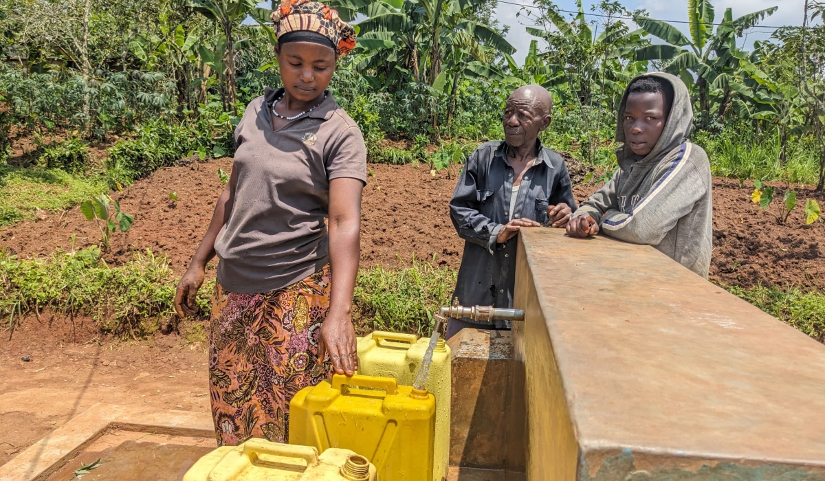 Providence Iradukunda, a resident of Mushonyi Sector in Rutsiro District, collects water as her village mates look on.