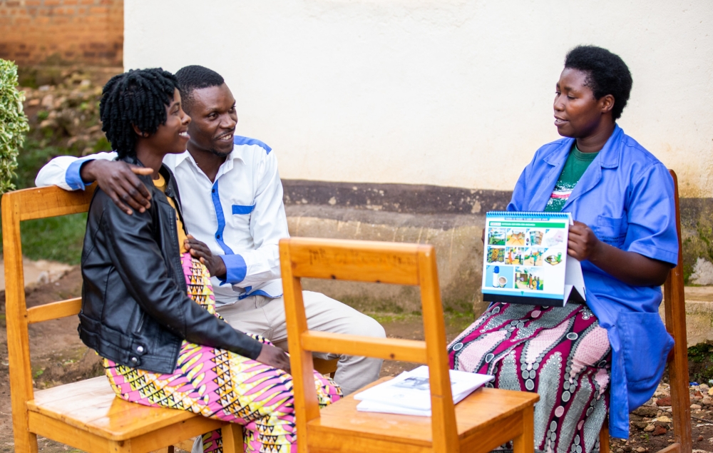 A pregnant woman with her husband meet with a community health worker for advice in Karongi District. Photo by Olivier Mugwiza