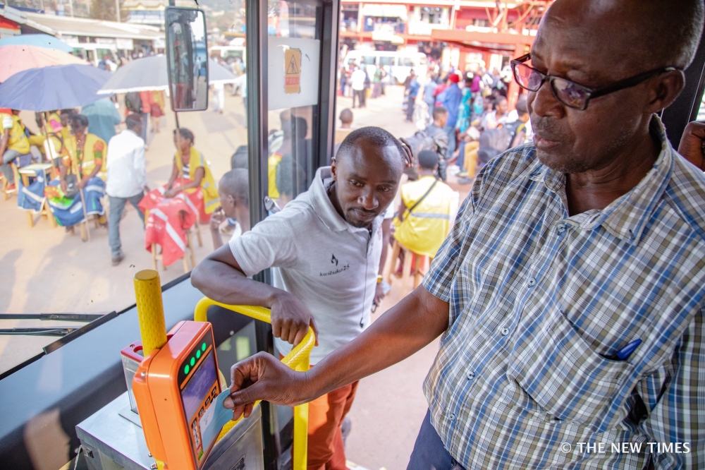 Commuters board a public bus at Nyabugogo taxi park in Kigali.  Officials have announced that the new public transport fares will take effect on March 16. Photo by Craish Bahizi