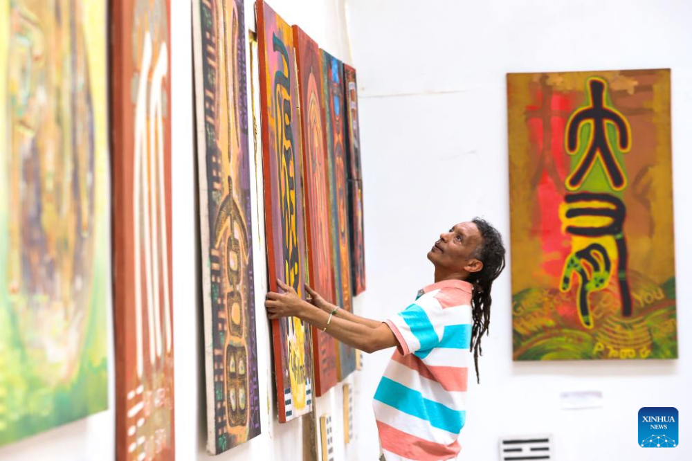Artist Dawit Muluneh hangs one of his Chinese-character paintings on the wall for exhibition at an art gallery in Addis Ababa, Ethiopia, March 18, 2024. (Xinhua/Michael Tewelde)