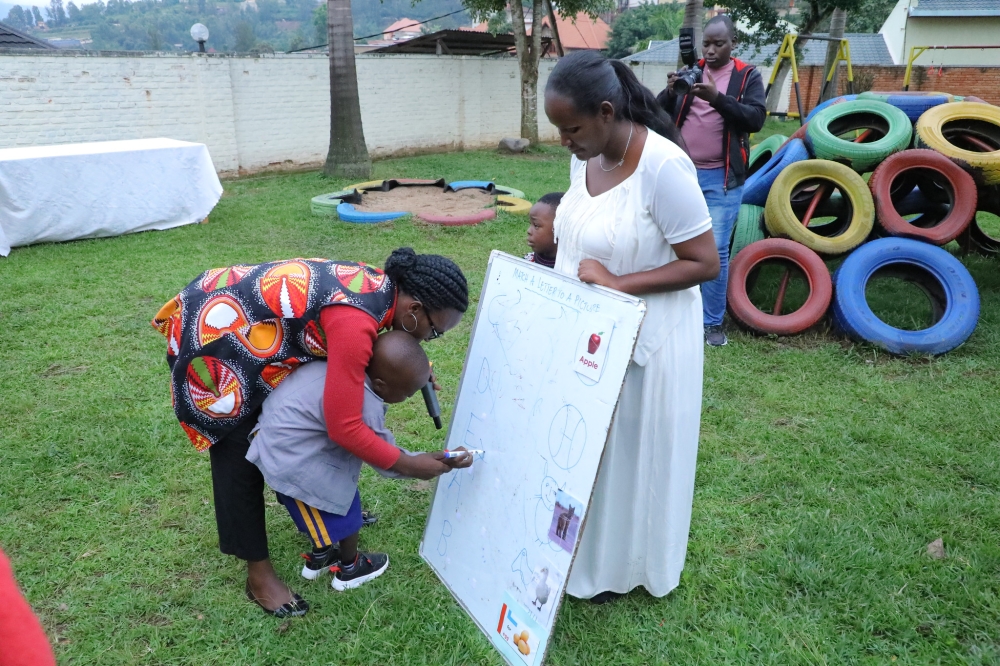 A parent helps a child to write at Autism Rwanda at Kagugu in Kigali. Photo by Craish Bahizi