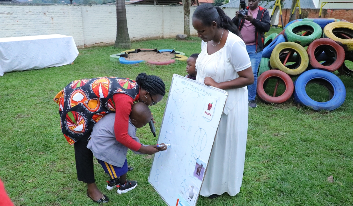A parent helps a child to write at Autism Rwanda at Kagugu in Kigali. Photo by Craish Bahizi