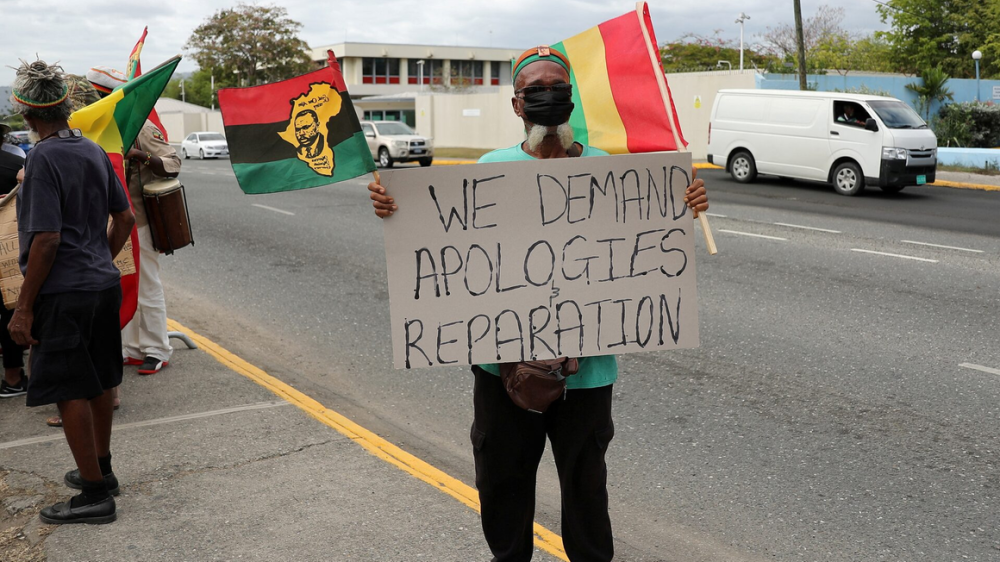 A protester holds a sign during a rally to demand that the United Kingdom make reparations for slavery, ahead of a visit to Jamaica by the Duke and Duchess of Cambridge as part of their tour of the Caribbean, outside the British High Commission in Kingston, Jamaica on March 22, 2022. PHOTO | REUTERS