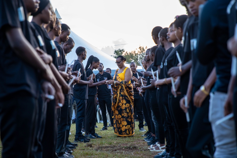 Speaker of Parliament Donatille Mukantabana is helped to light a candle in memory of Genocide victims interred at Nyanza Genocide Memorial in Kicukiro District on Thursday, April 11. Nyanza memorial is the final resting place of over 100,000 victims of the Genocide against the Tutsi. DAN KWIZERA