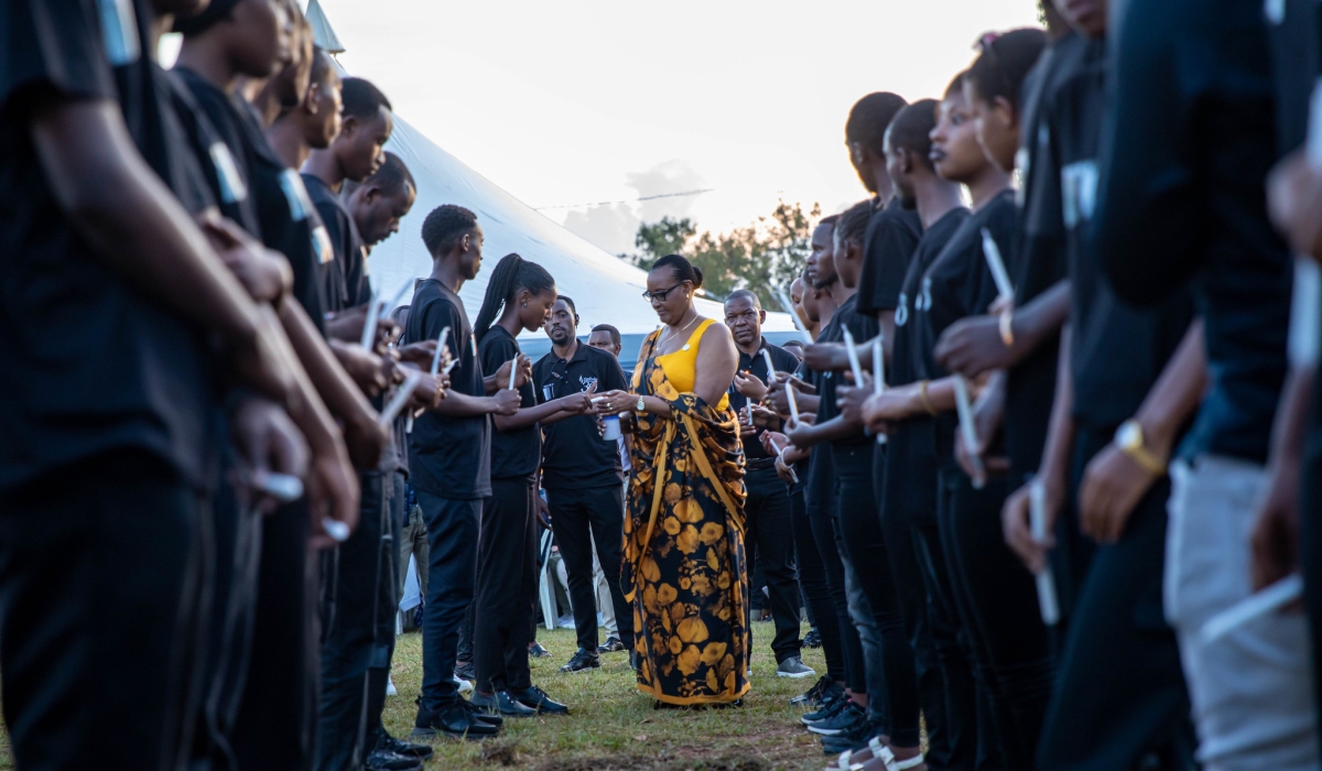 Speaker of Parliament Donatille Mukantabana is helped to light a candle in memory of Genocide victims interred at Nyanza Genocide Memorial in Kicukiro District on Thursday, April 11. Nyanza memorial is the final resting place of over 100,000 victims of the Genocide against the Tutsi. DAN KWIZERA