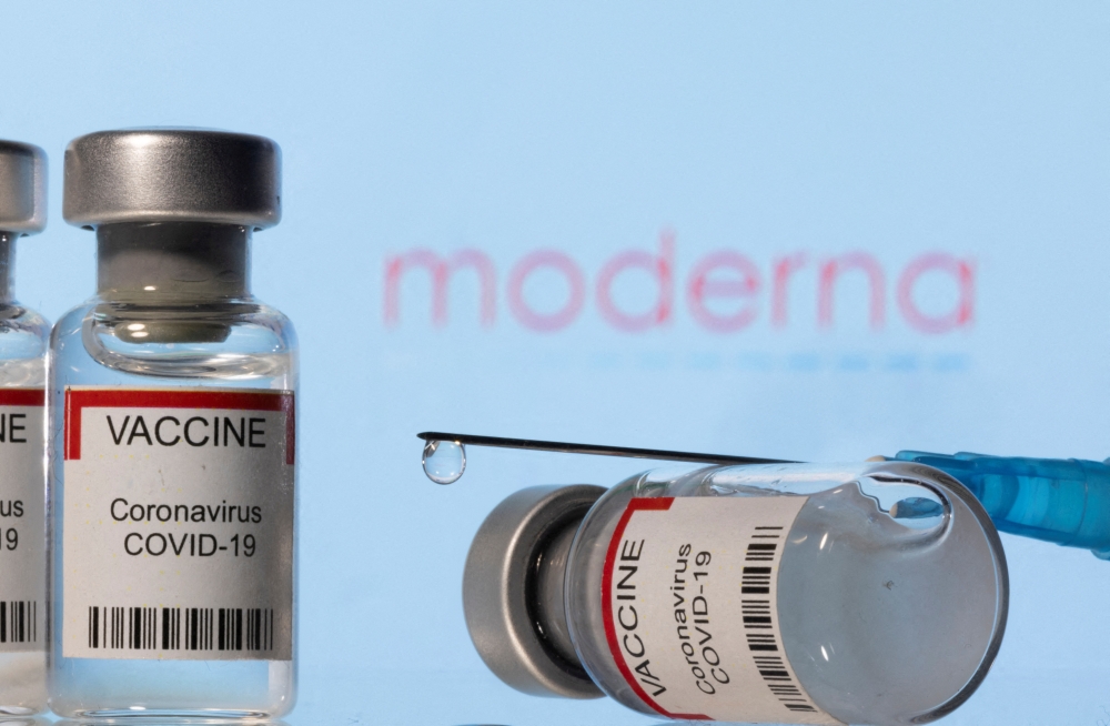 ials labelled "VACCINE Coronavirus COVID-19" and a syringe are seen in front of a displayed Moderna logo in this illustration taken December 11, 2021. REUTERS/Dado Ruvic