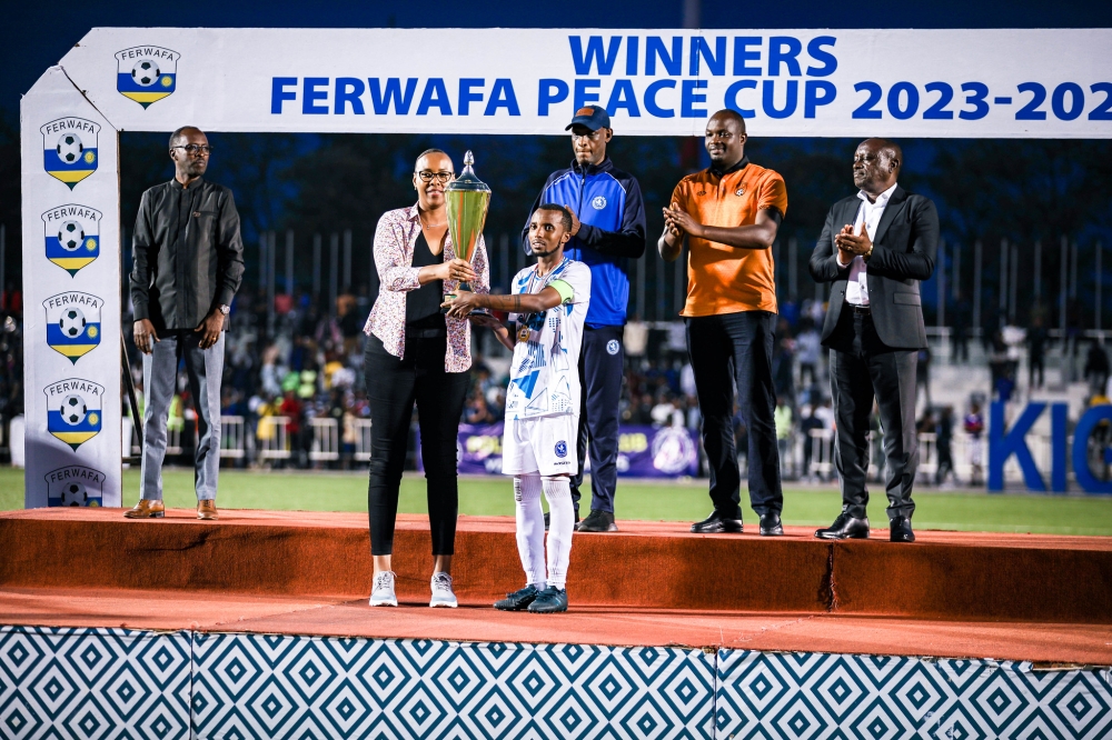 Minister of Sports hands over the trophy to Police FC captain Dominique Savio Nshuti (R) at Kigali Pele stadium on May 1. Photo by Craish Bahizi