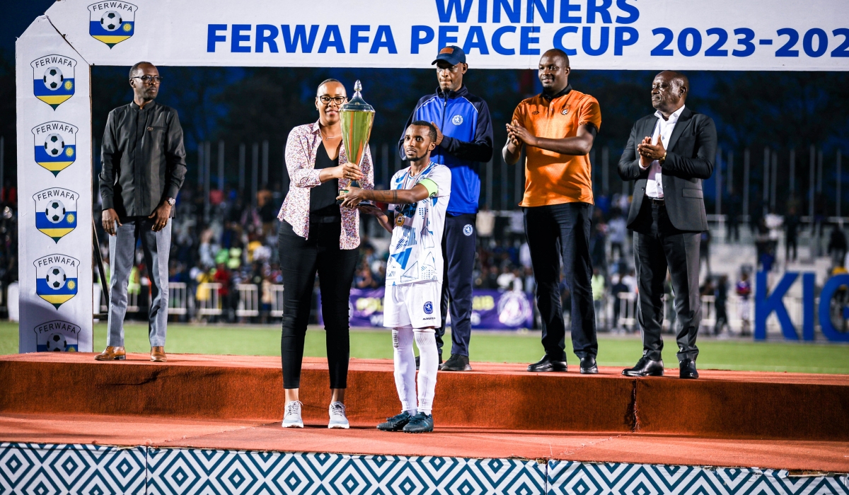Minister of Sports hands over the trophy to Police FC captain Dominique Savio Nshuti (R) at Kigali Pele stadium on May 1. Photo by Craish Bahizi
