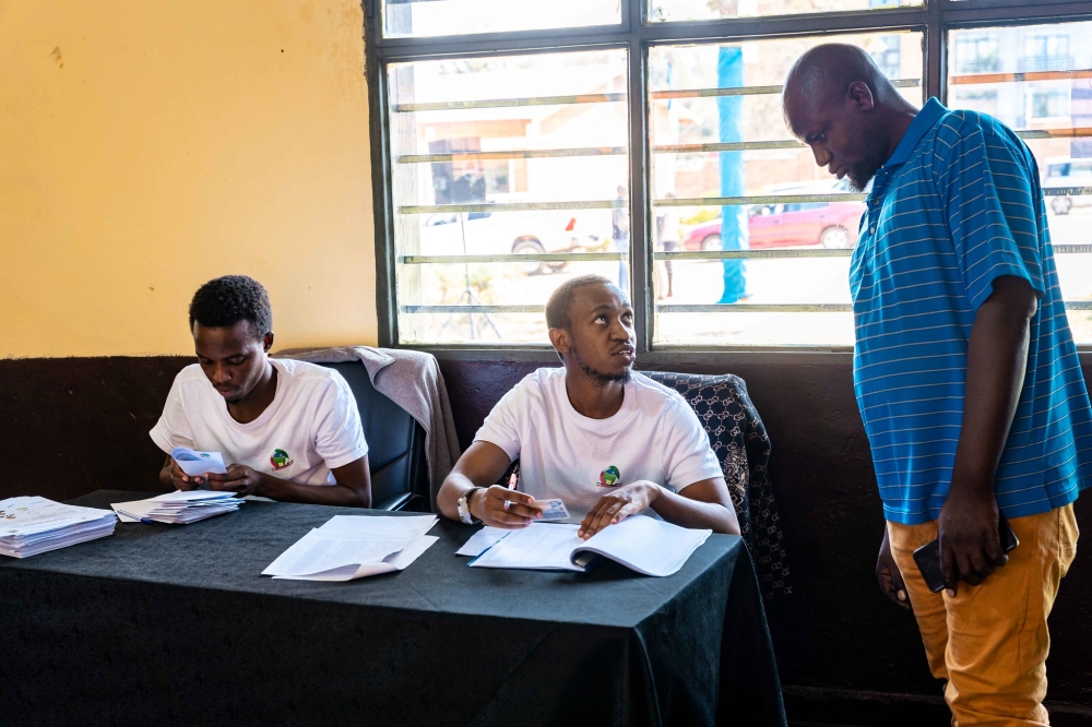 NEC volunteers help a voter before csting his vote during the presidential and parliamentary elections, on July 15. Photo by Craish Bahizi
