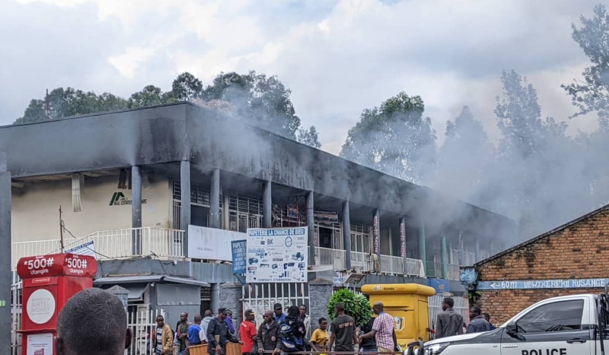 Police officers escort people away from the scene of a fire outbreak on a commercial building in Musanze town. Courtesy
