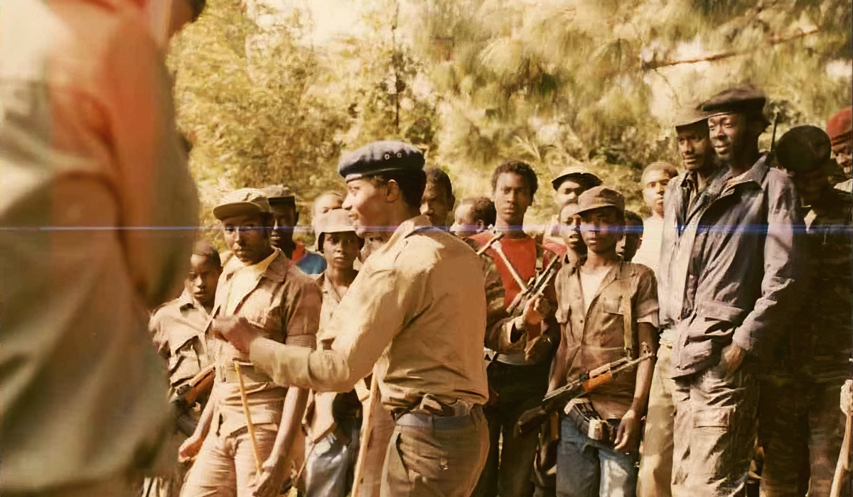 Late Commander Mico (with a pistol), then commander of Charlie Mobile Force speaking to Rwanda Patriotic Army fighters during the Liberation War at Mountain Sabyinyo in 1991. File