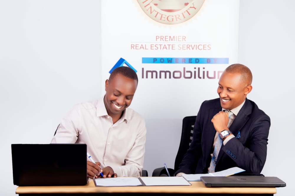 Celestine Uwineza- Managing Director of Premier Real Estate Services (L), and Fred Agaba Operations Manager at Premier Real Estate Services sign the  partnership agreement in Kigali. Courtesy