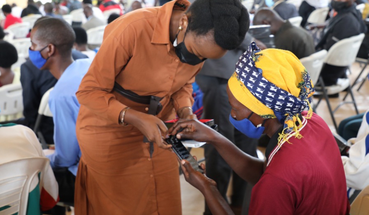 Minister of ICT and Innovation Paula Ingabire helps a resident to switch on a smartphone in Bugesera District .Mobile phone ownership in Rwanda has increased to 85 per cent in 2024, up from 67 per cent in 2017.