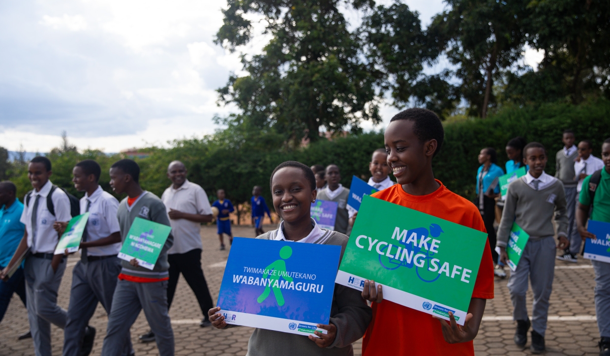 Students from Kigali Christian School hold posters advocating for safer streets for pedestrians and cyclists during a walk organized by HPR