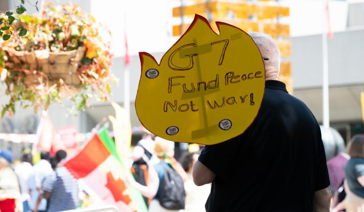 A protester holds a sign during a rally in Calgary, Canada, June 15, 2025. (Photo by Li Haitao/Xinhua)