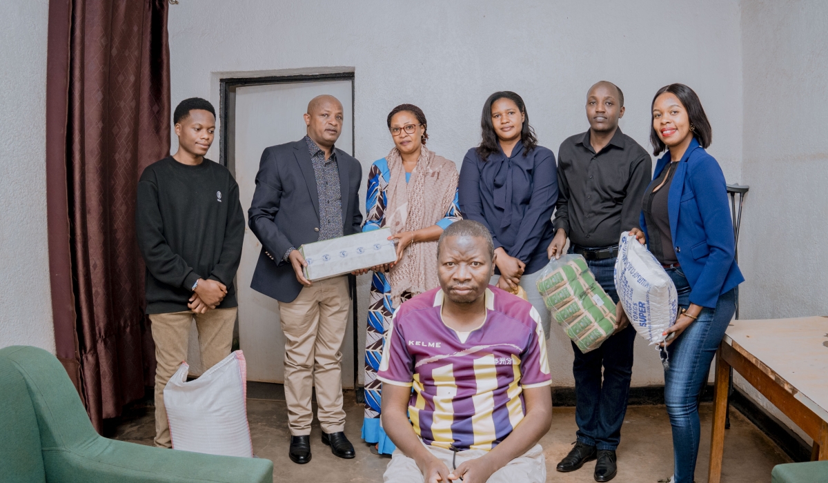 Dr John Nyirigira (second from left) hands over foodstuffs to Claudine Umutoni (third from left) during a visit by university staff to her home.
