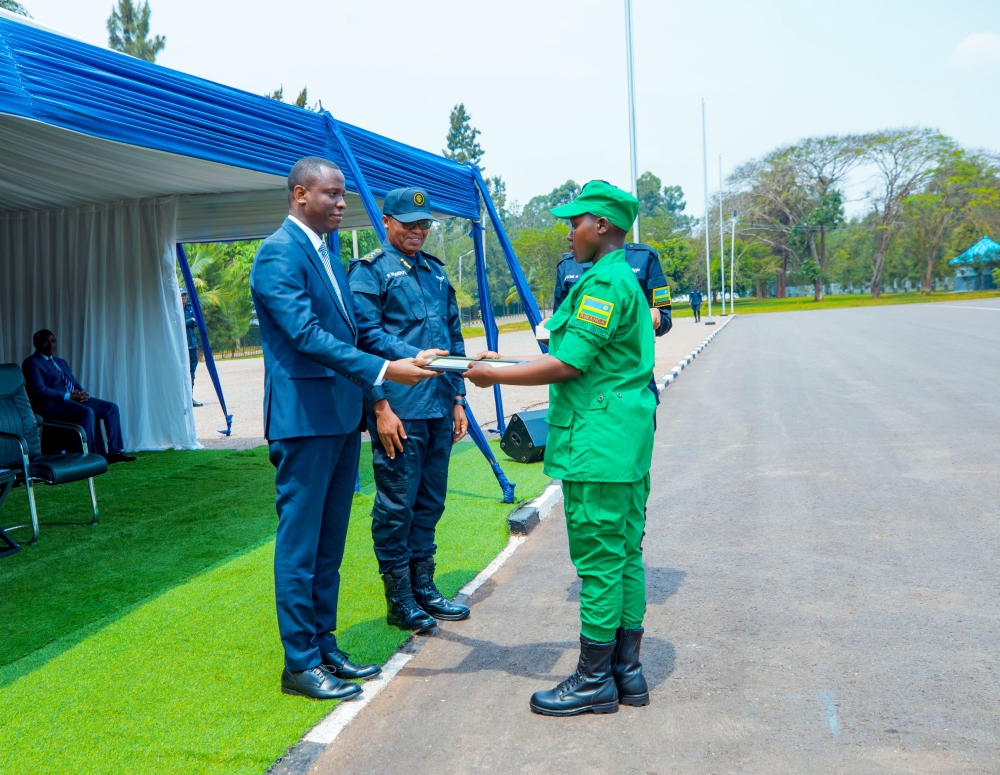 The Minister of Local Government, Dominique Habimana hands over a certificate of completion to the best performer of the training