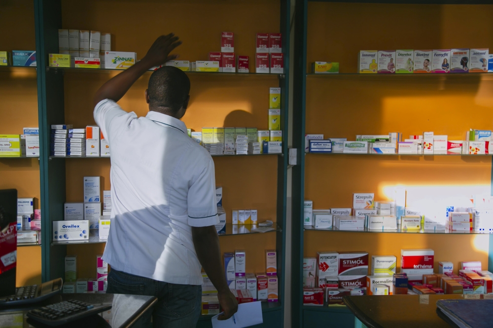 A pharmacist searching rows of drugs at Kisimenti in Kigali. Photo by Craish BAHIZI