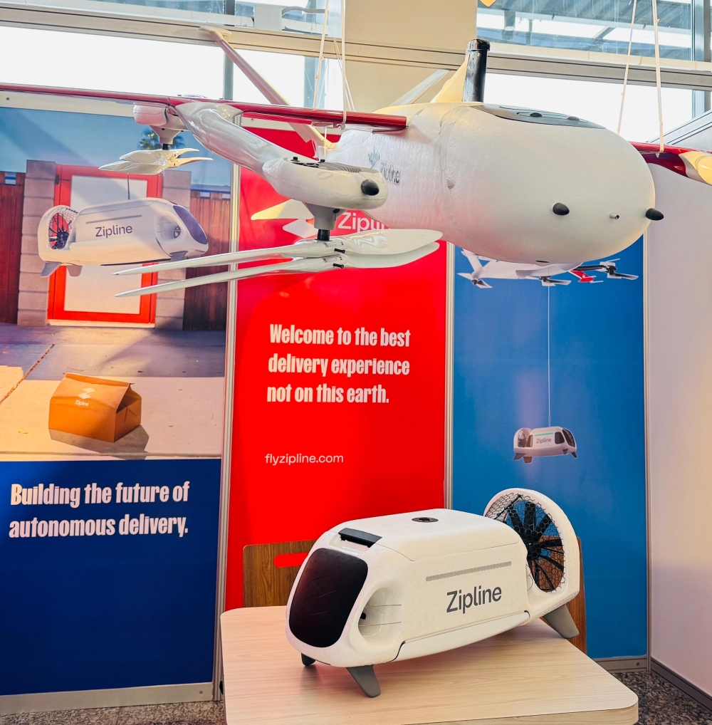 American unmanned aerial logistics firm Zipline’s next-generation autonomous aircraft designed specifically for urban delivery, on display at the Aviation Africa Summit, in Kigali, on September 4, 2025. The device on the table, which holds a package, is fitted into the drone and lowered when it reaches a destination to safely deliver a package (Emmanuel Ntirenganya)