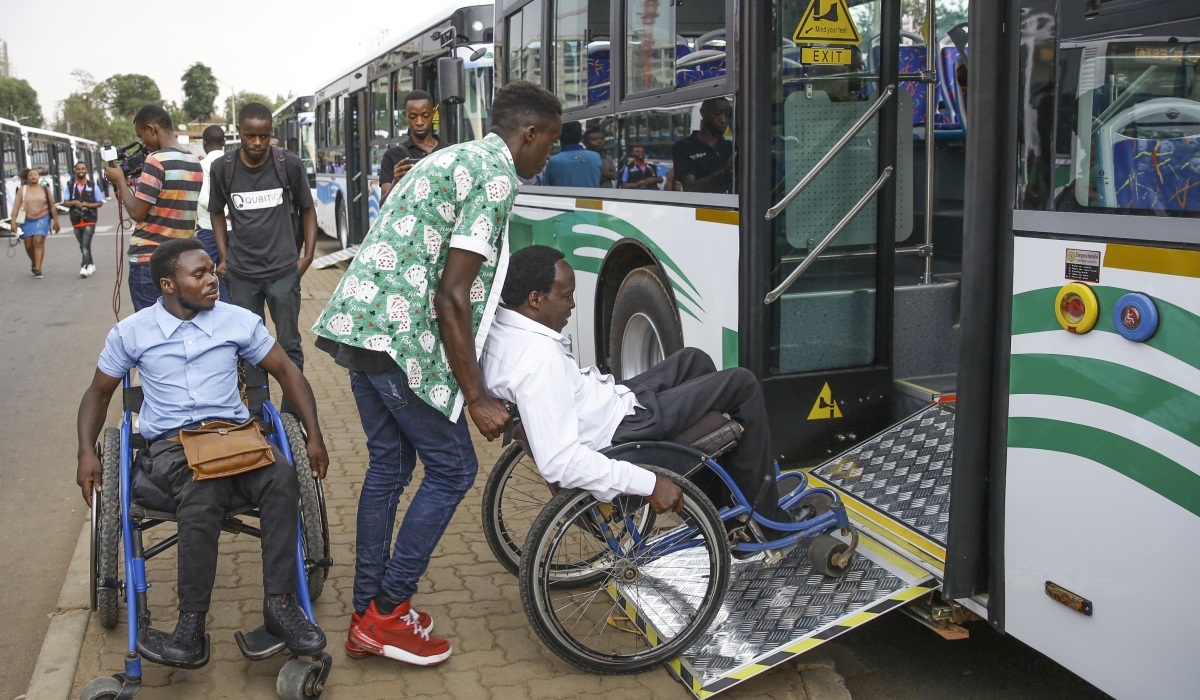 People assisting people with disabilities as they board a public bus in Kigali. Craish Bahizi