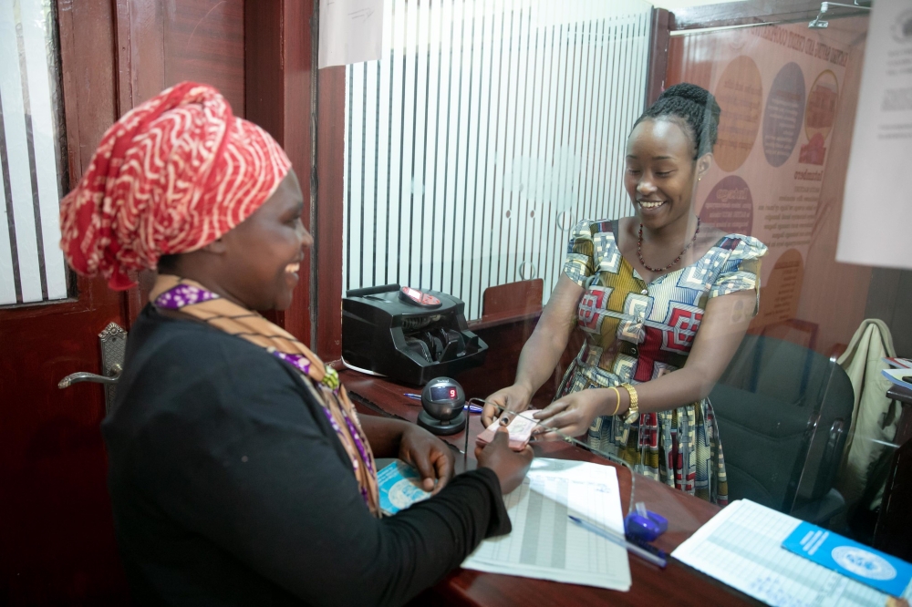 A woman receives her money during a transaction activity at Umurenge SACCO Kacyiru. File