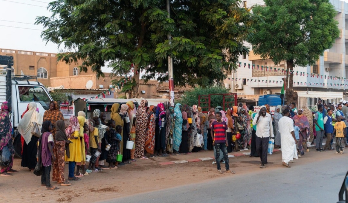 Recently displaced families queue for a food distribution alongside long-term residents in Omdurman, Sudan's second largest city.