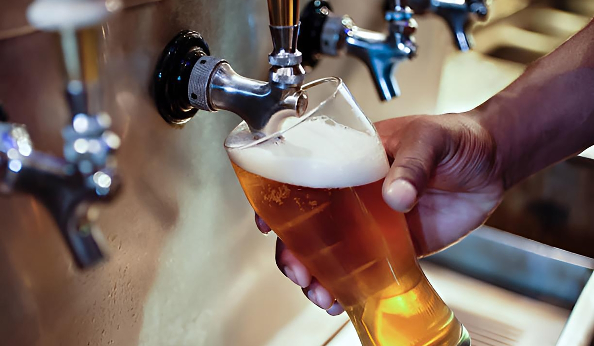 A person pouring beer into a glass. The Ministry of Health’s “Tunywe Less” campaign is a bold initiative promoting responsible drinking and raising awareness about addiction. Internet Photo