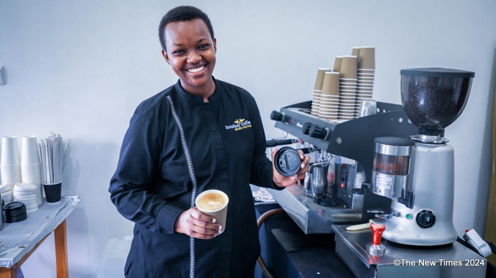 A barista smiles as she prepares a cup of coffee at Bourbon Coffee in Kigali. Photo by Craish Bahizi.