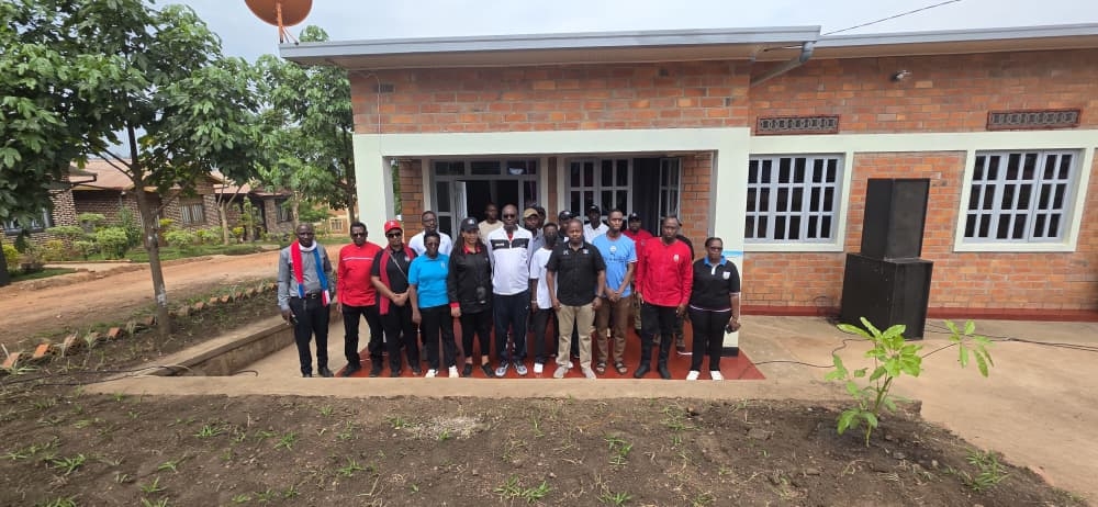 City of Kigali employees pose infront of the new house built for the vulnerable resident. Courtesy.