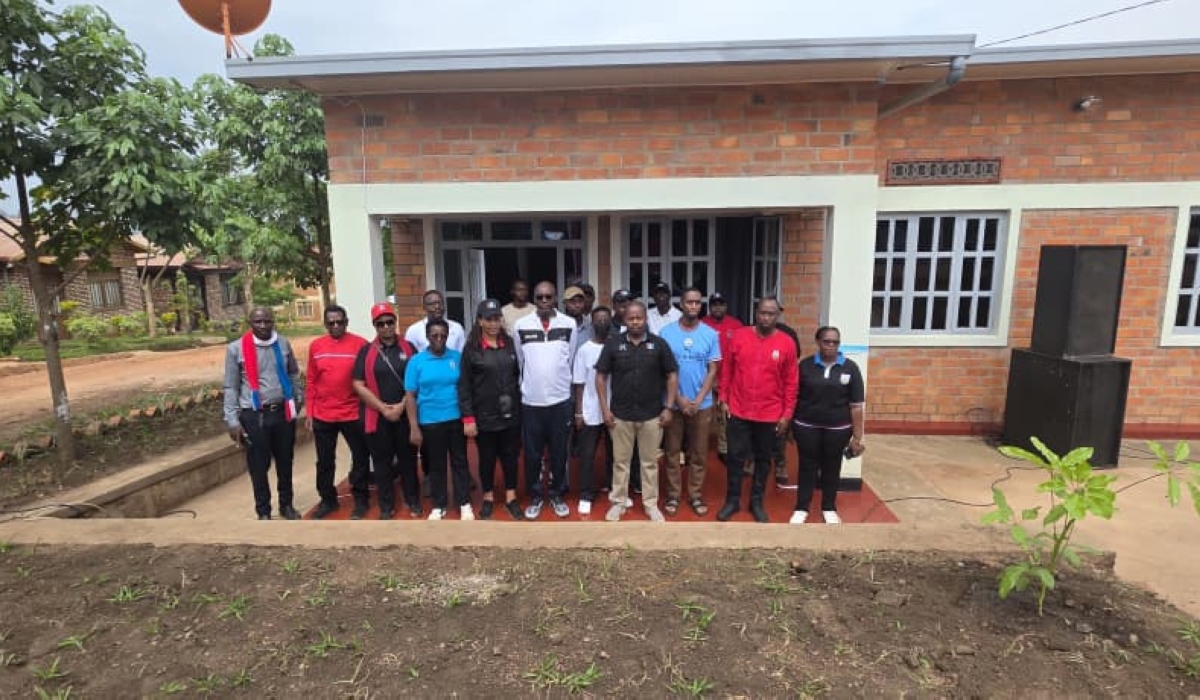 City of Kigali employees pose infront of the new house built for the vulnerable resident. Courtesy.