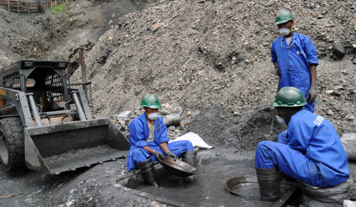 Workers at a mining site sift through mineral-rich soil using traditional panning techniques, as machinery operates nearby to support the extraction process. Courtesy 
