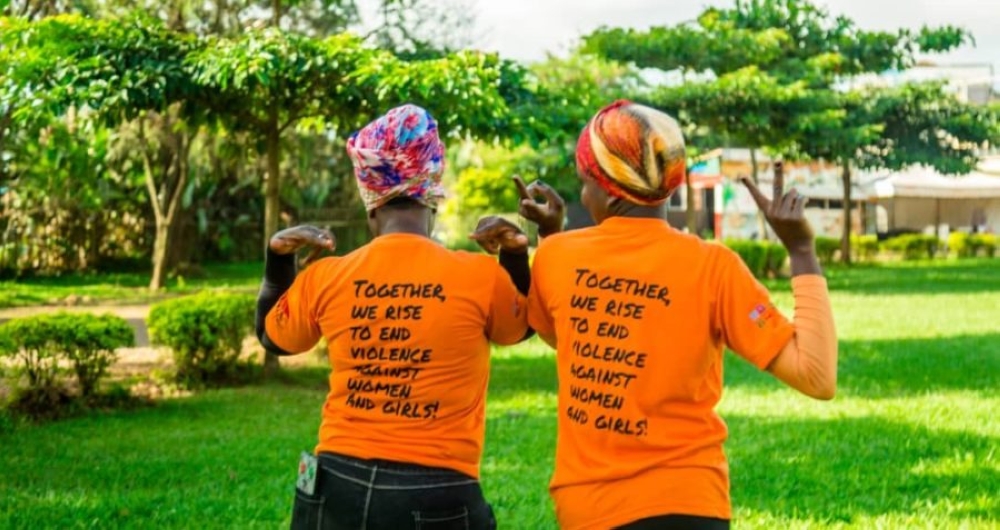 Two women proudly wear the message: ‘Together, we rise to end violence against women and girls,’ standing strong for change and hope.
