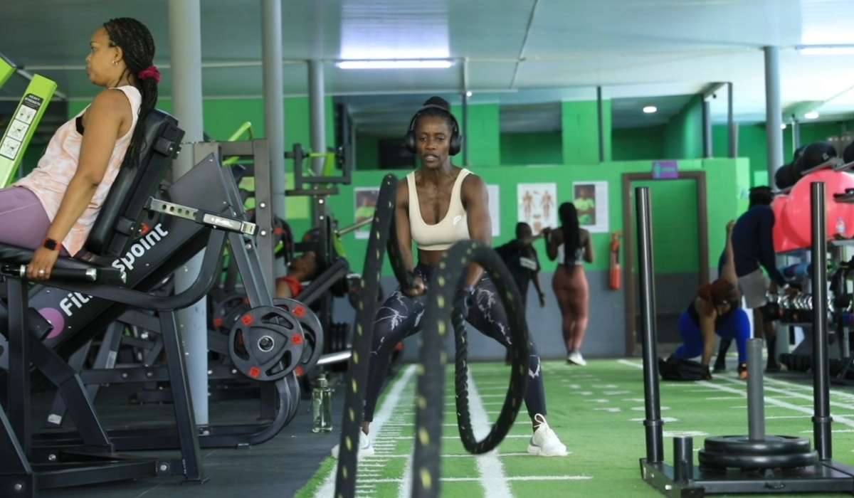 A woman works out with battle ropes at a busy gym, as others train on strength and cardio equipment. A 30-minute workout can help reduce stress, lower cortisol levels, and speed up recovery. Photo by Craish Bahizi