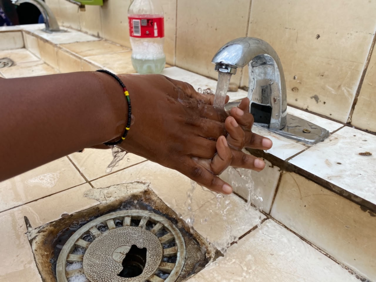 A woman washes her hands at a handwashing station at the entrance of Nyabugogo Taxi Park