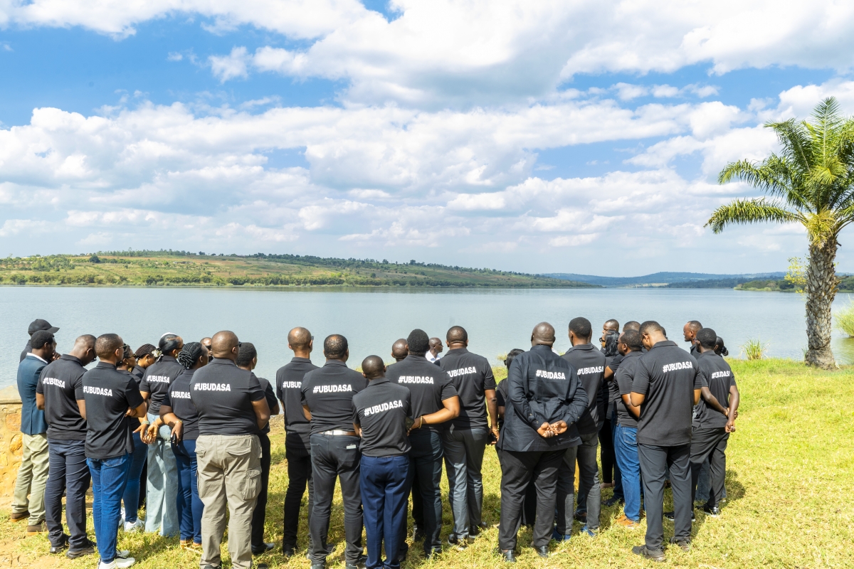 Members of Ubudasa Club listen as Raymond Habimana shares testimony at Lake Mugesera.
