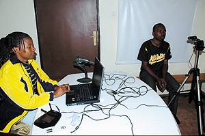  Jacqueline Akayezu (L) works on the particulars of Ferdinand Uwizeyimana at Muhima as the latter is photographed for an electronic ID Card yesterday.(Photo/ J. Mbanda)
