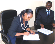 Linda Bihire the new infrastructure minister signing instruments of power allowing her to be the political head of the ministry as Ambassador Kamanzi, former head of the ministry looks on. (Courtesy photo).