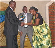 James Musoni, Finance and Economic Planning Minister (L) awards a certificate of recognition to Mary Baine, Rwanda Revenue Authority (RRA) Commissioner General for heading the tax body for a decade. Looking on is Ephraim Turahirwa, Chairman board of Direc