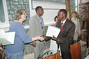 Patrick Musimolya receives a Certificate from the US Embassy Charge du2019Affaire Cherly Sim at the end of a seminar for Trainers of Primary School English Teachers, as the General Inspector of Education Narcise Musabeyezu looks on (Photo/ J Mbanda).