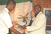 The Chairman Board of Directors Riviera High School, Charles Karake, hands over a certificate to a student. (Photo/ G.Barya).