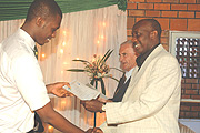 The Chairman Board of Directors Riviera High School, Charles Karake, hands over a certificate to a student. (Photo/ G.Barya).