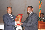 Vincent Karega, State Minister for Industry and Investment Promotion (L) receiving a trophy from Robert Bayigamba, President of the Private Sector Federation.(Courtesy photos)