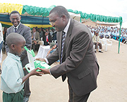 A child receives a Laptop from Minister Mutsindashyaka as Minister Romain Murenzi looks on. (Photo/ J. Mbanda)