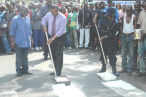 The acting Commissioner General of Police, Mary Gahonzire, with MTN CEO,  Themba Khumalo, painting a Zebra crossing to launch the traffic safety week  yesterday. (Photo/ G. Barya).