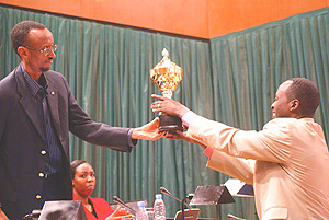 President Paul Kagame giving a trophy to Nyamagabe mayor Alphonse Munyantwari after his district emerged the best in implementing performance contracts. (Photo/G.Barya).
