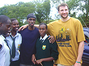 Rwandau2019s Basketball Captain Hamza Ruhezamihigo (with cap) and Rob Thomson pose for a photo with Green Hills academy students.