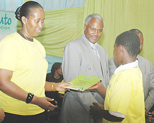 First Lady Jeannette Kagame hands a certificate to Clu00e9mentine Mukashyaka, one of the best performing Girls in Gicumbi District as Minister Murigande looks on. (Photo/G. Barya)